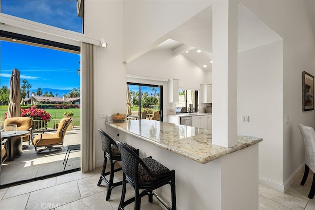 283 Wild Horse Dr, Palm Desert, CA 92211 - kitchen featuring white cabinetry, light stone counters, dishwasher, high vaulted ceiling, and light tile patterned floors