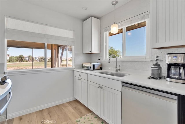 kitchen featuring stainless steel dishwasher, a healthy amount of sunlight, a sink, and light wood-type flooring