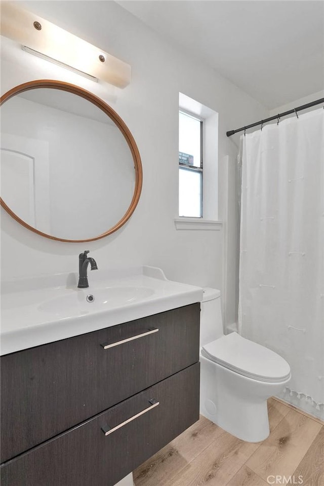 bathroom featuring vanity, a shower with shower curtain, wood finished floors, and toilet