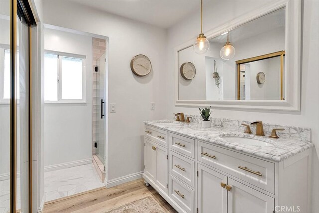 full bath featuring a sink, baseboards, a stall shower, and double vanity