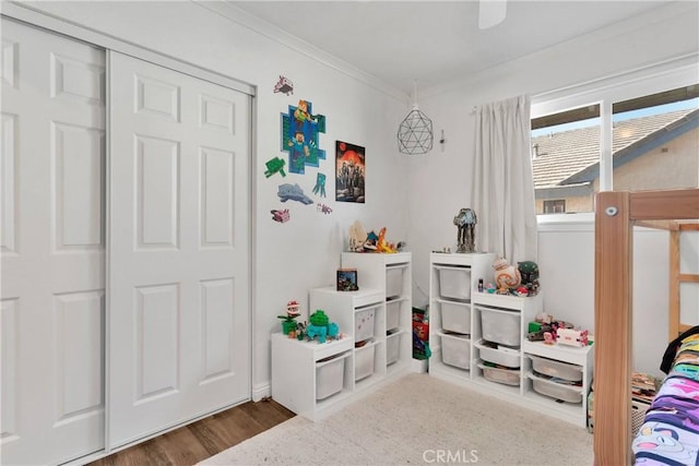 bedroom with ornamental molding, wood finished floors, and a closet