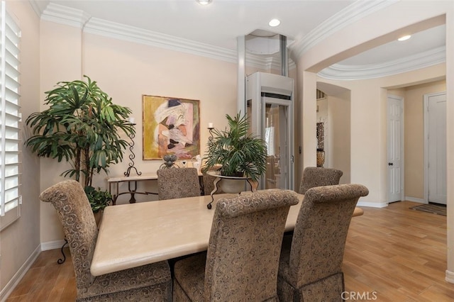 dining room with wood finished floors, crown molding, and baseboards