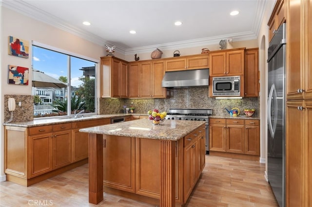 kitchen featuring built in appliances, a center island, under cabinet range hood, light stone countertops, and brown cabinetry