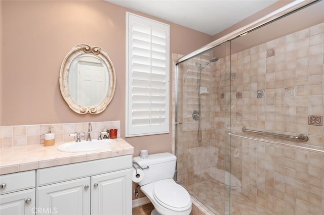 bathroom with a shower stall, toilet, and vanity