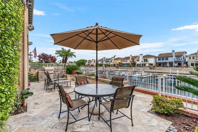 view of patio / terrace with a residential view, outdoor dining area, a water view, and fence