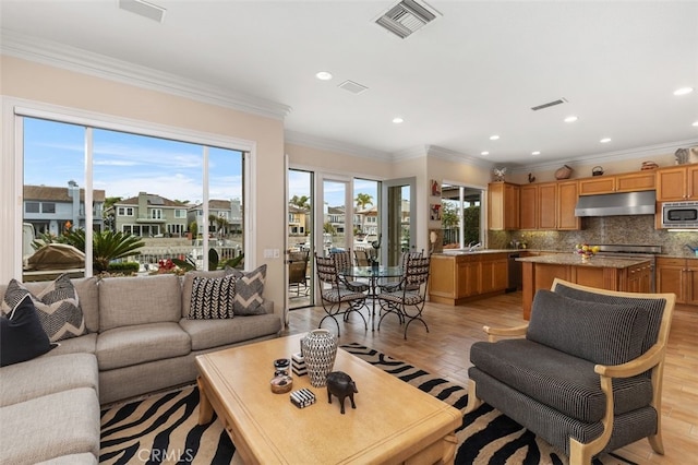 living room with visible vents, ornamental molding, light wood-style flooring, and recessed lighting