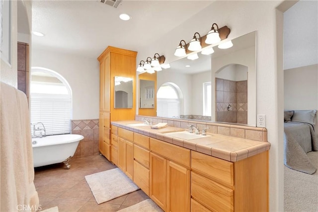 full bathroom featuring a sink, double vanity, tile walls, visible vents, and tile patterned flooring