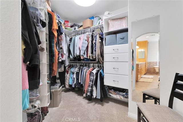 spacious closet featuring arched walkways and carpet floors