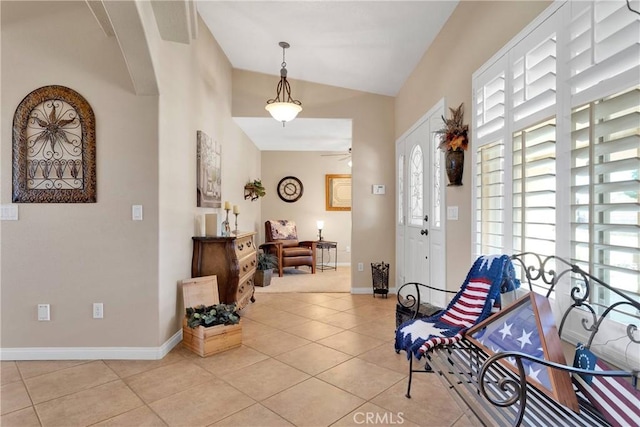 entryway featuring baseboards, vaulted ceiling, a ceiling fan, and light tile patterned floors