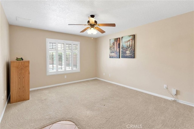 unfurnished room with visible vents, a ceiling fan, baseboards, a textured ceiling, and carpet flooring