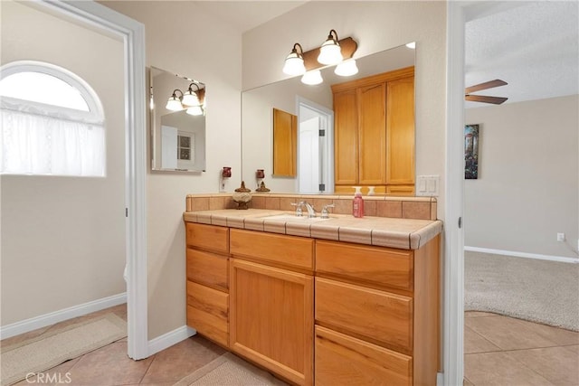 bathroom with a ceiling fan, baseboards, tile patterned flooring, and vanity