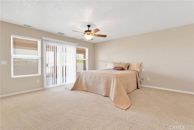 carpeted bedroom featuring a textured ceiling, visible vents, a ceiling fan, and baseboards