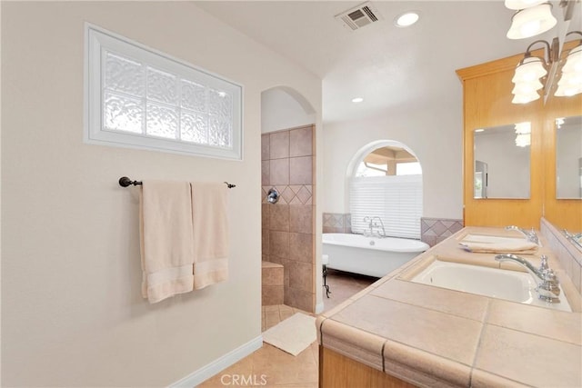 full bath with a freestanding tub, walk in shower, visible vents, and a sink
