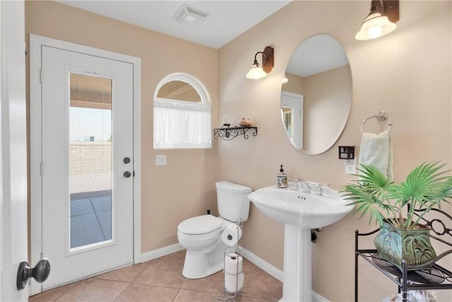 half bath with toilet, tile patterned flooring, visible vents, and baseboards