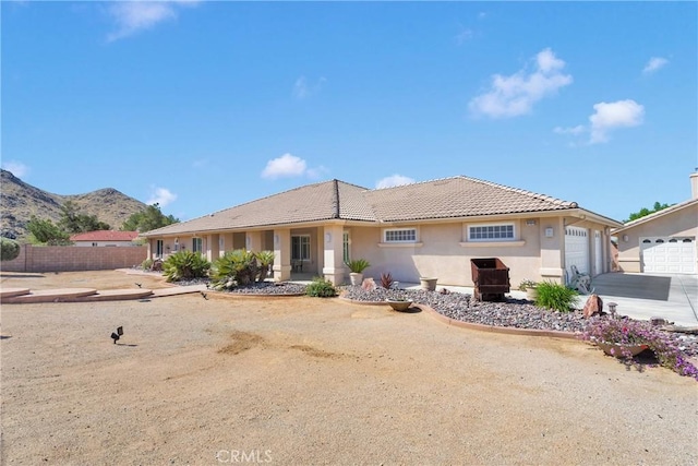 view of front of home featuring an attached garage, a tile roof, fence, and stucco siding