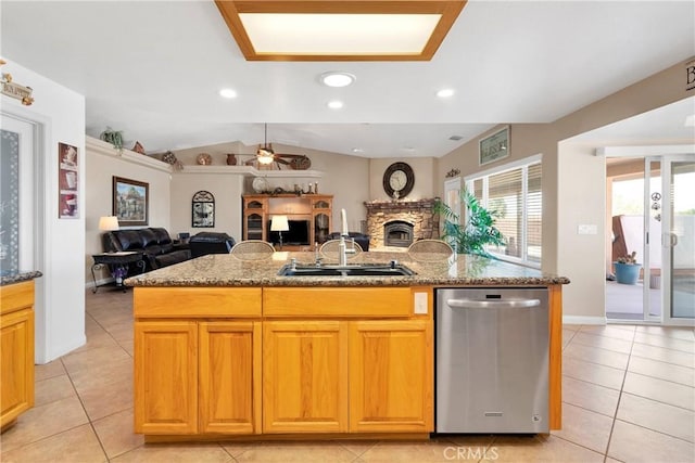 kitchen featuring stainless steel dishwasher, a sink, a fireplace, open floor plan, and ceiling fan