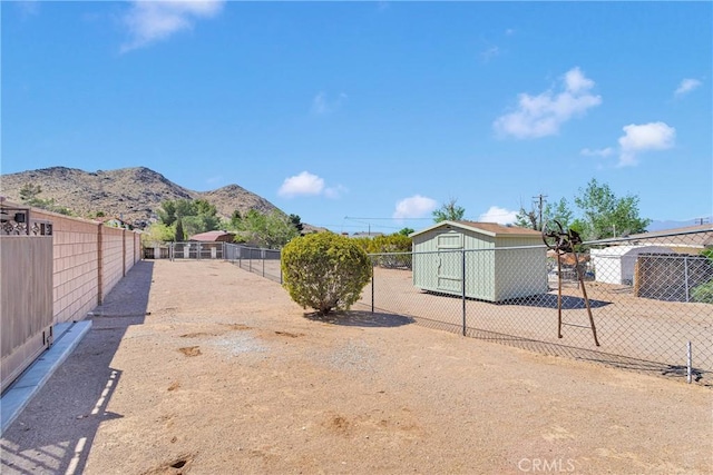 view of yard with a fenced backyard, an outbuilding, a mountain view, and a shed