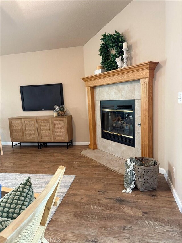 living room with baseboards, wood finished floors, and a tiled fireplace