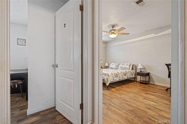 bedroom featuring baseboards, wood finished floors, visible vents, and a ceiling fan