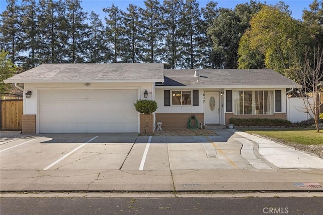 single story home with brick siding, fence, driveway, and a garage