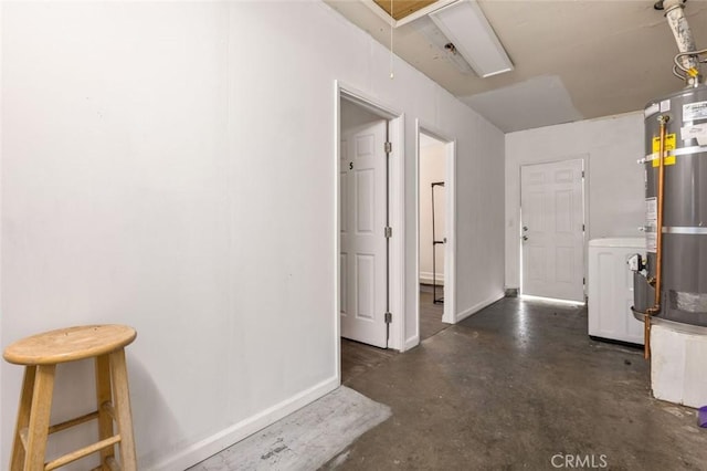 hallway featuring attic access, strapped water heater, baseboards, concrete floors, and washer / dryer