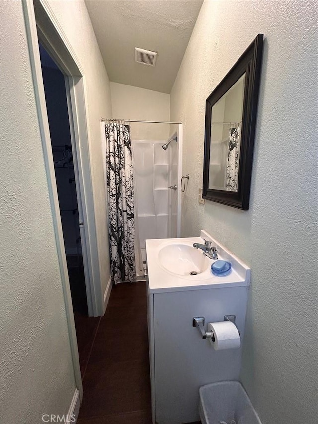 bathroom featuring baseboards, a textured wall, vanity, and visible vents