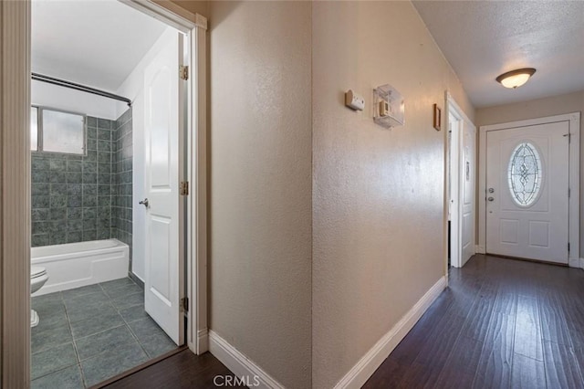 interior space with baseboards, a textured wall, and wood finished floors