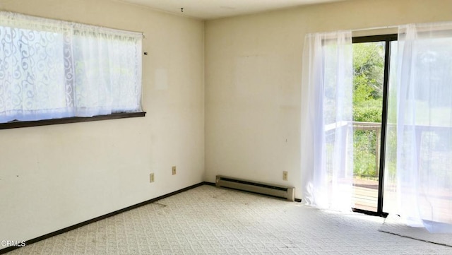 spare room with baseboard heating, carpet floors, and baseboards