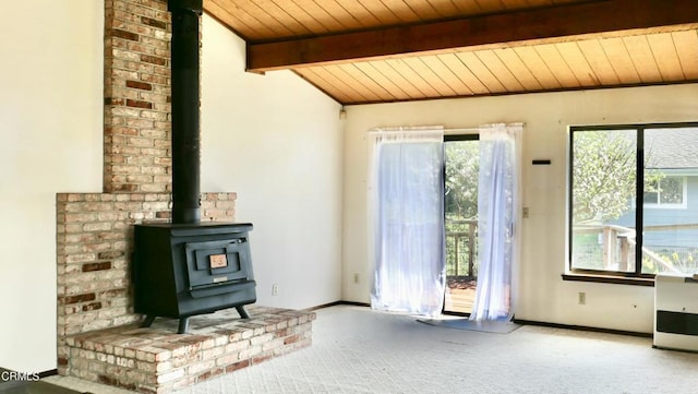 unfurnished living room featuring carpet, a wood stove, wooden ceiling, and plenty of natural light