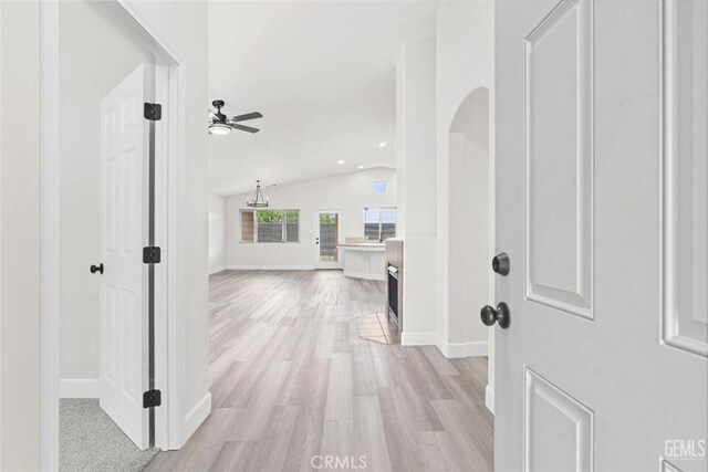 corridor with vaulted ceiling, light wood finished floors, and baseboards