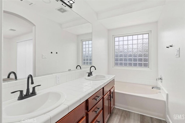 full bathroom with visible vents, wood finished floors, a sink, and double vanity
