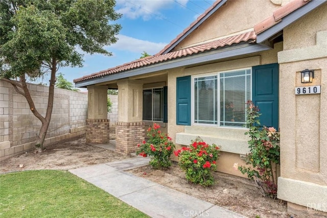 view of side of home with fence, a tile roof, and stucco siding