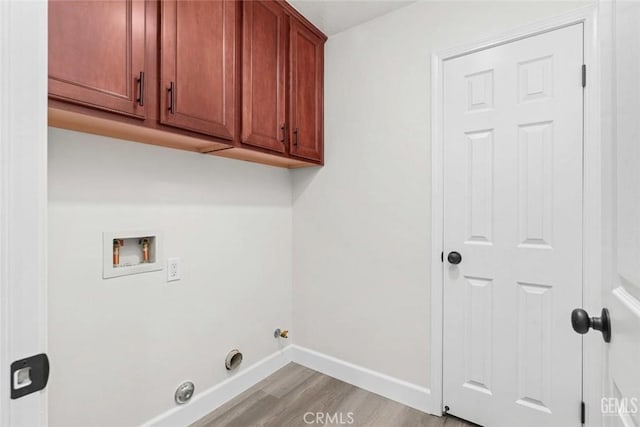 clothes washing area featuring light wood-type flooring, baseboards, washer hookup, hookup for a gas dryer, and cabinet space