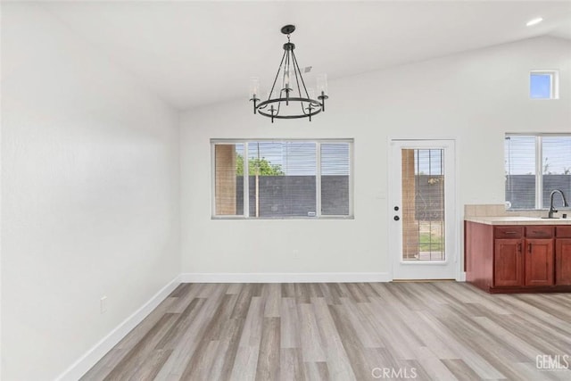 unfurnished dining area with light wood-type flooring, baseboards, a sink, and a chandelier