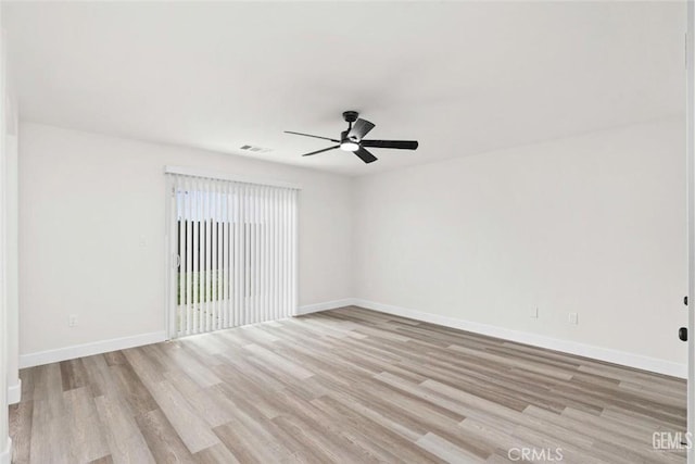 spare room featuring light wood finished floors, a ceiling fan, baseboards, and visible vents