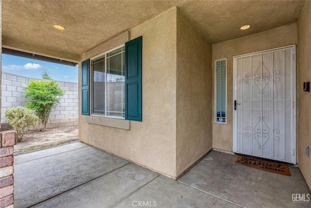 view of exterior entry featuring a patio and stucco siding