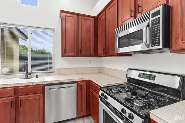 kitchen featuring stainless steel appliances, a sink, and tile countertops