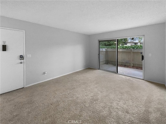 spare room with carpet floors, a textured ceiling, and baseboards