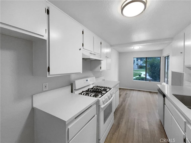 kitchen featuring white cabinetry, white range with gas cooktop, wood finished floors, light countertops, and under cabinet range hood