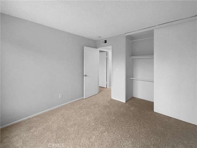 unfurnished bedroom with visible vents, carpet flooring, a textured ceiling, and a closet
