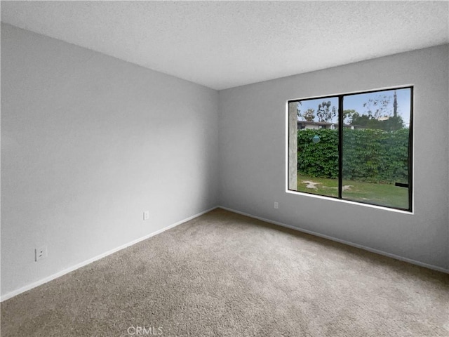 carpeted spare room with a textured ceiling and baseboards