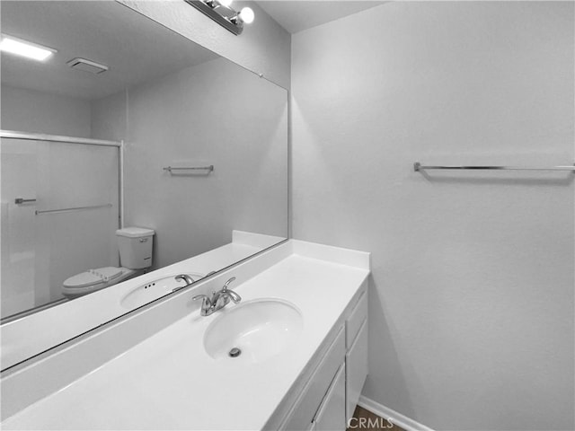 bathroom with a shower stall, toilet, and vanity