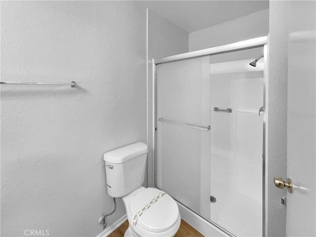 full bathroom with wood finished floors, toilet, and a stall shower