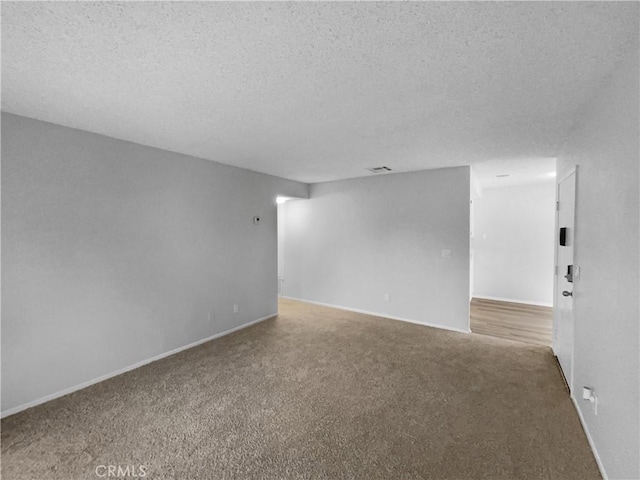empty room featuring baseboards, carpet flooring, a textured ceiling, and visible vents