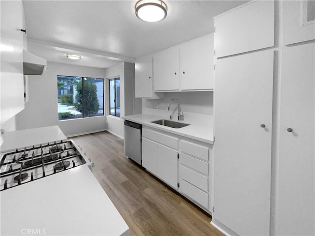 kitchen with stainless steel dishwasher, wood finished floors, a sink, light countertops, and white cabinetry