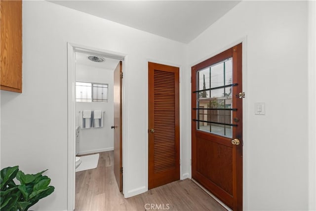 doorway with baseboards and light wood-type flooring