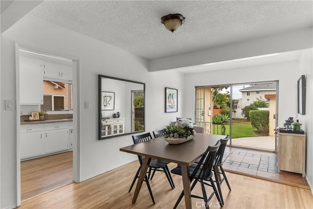 dining space featuring a textured ceiling and light wood-type flooring