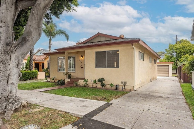 bungalow-style house with a detached garage, a front lawn, and stucco siding