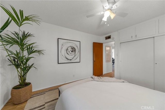 bedroom featuring light wood finished floors, baseboards, visible vents, a ceiling fan, and a closet