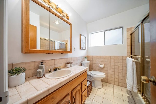 bathroom with tile patterned floors, a stall shower, vanity, tile walls, and toilet
